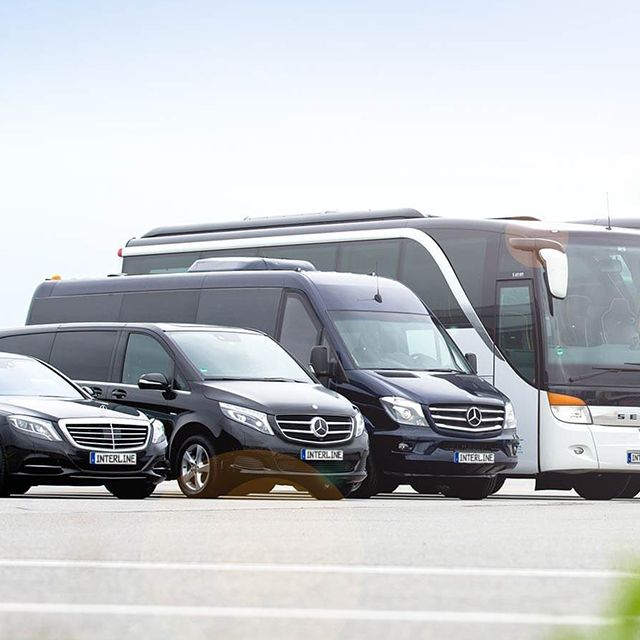 Reisebusse und Minivans auf dem Rollfeld vor einem Flugzeug.