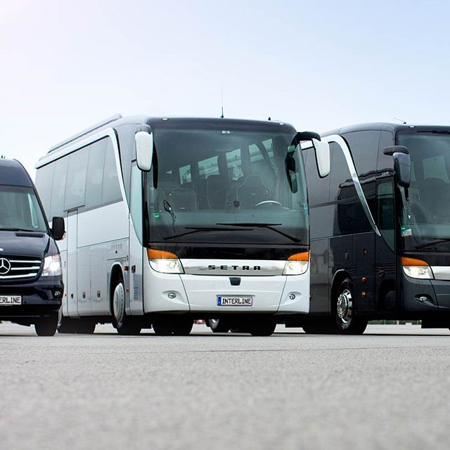 Reisebusse und Minivans auf dem Rollfeld vor einem Flugzeug.